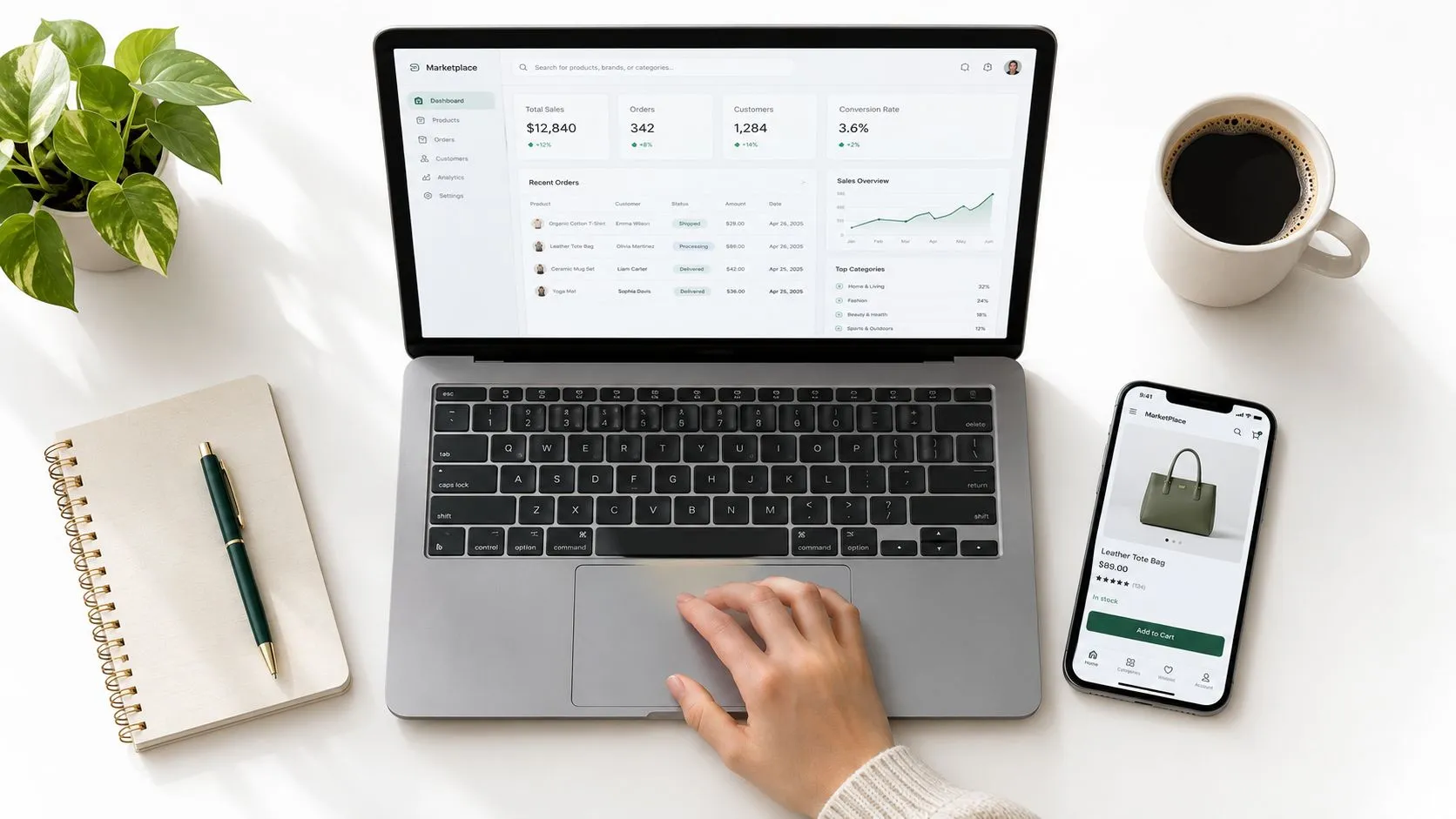 Persona trabajando en una computadora portátil con un tablero de ventas junto a un teléfono inteligente.