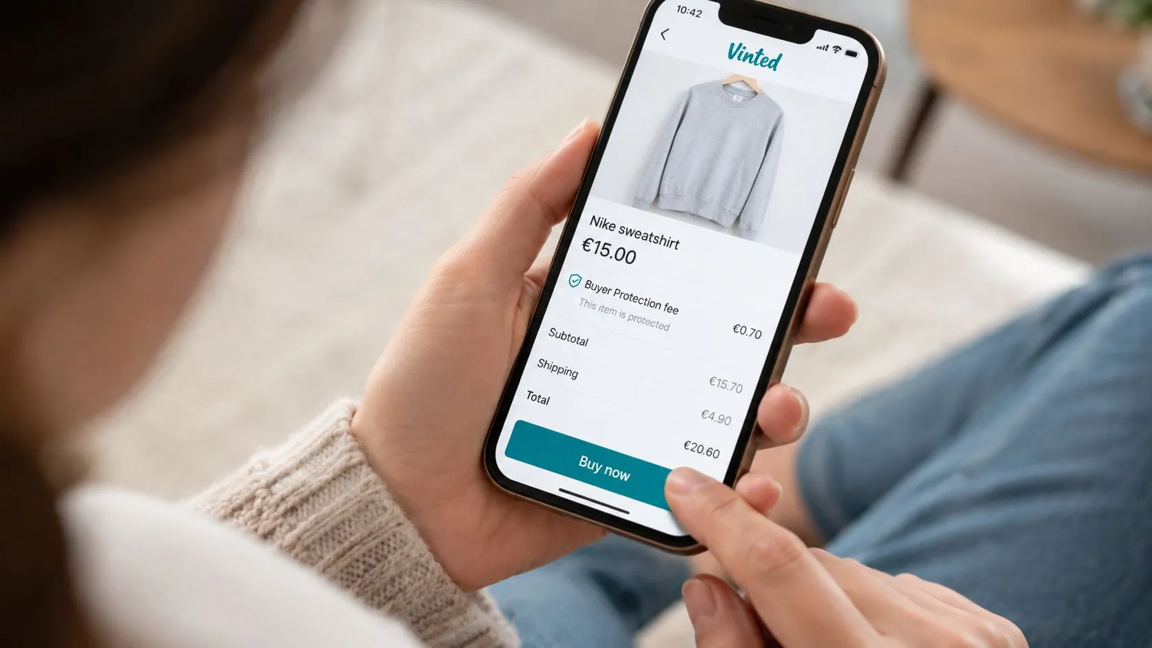 Une personne utilisant l'application Vinted sur son smartphone pour finaliser l'achat d'un sweat-shirt Nike en ligne.